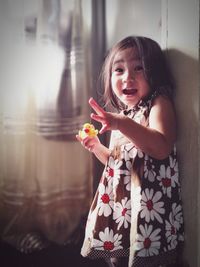 Portrait of shocked cute girl holding rubber duck