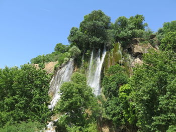 Scenic view of waterfall in forest against sky