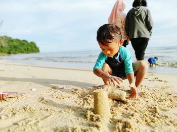 Side view of boy playing with sand at beach