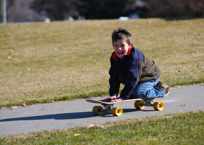 Full length of boy skateboarding on footpath at park