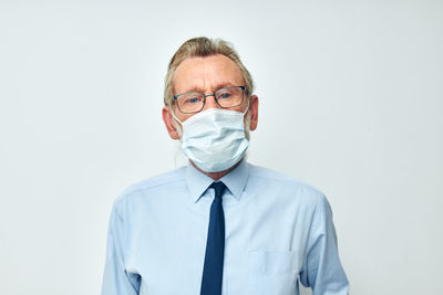 Portrait of senior man wearing mask against white background