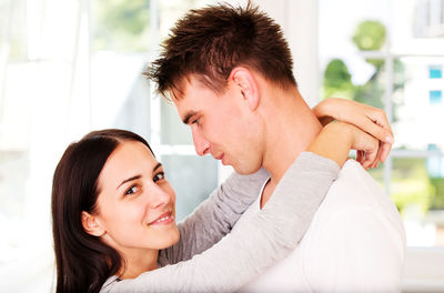 Young couple romancing while standing by window at home