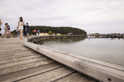 People on pier against sky