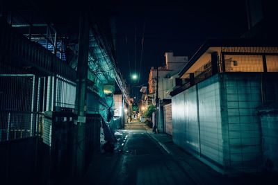 Empty alley by buildings in city at night