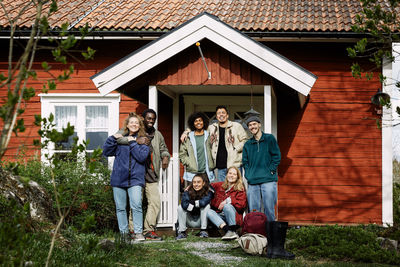 Portrait of happy male and female friends at house entrance