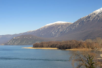 Scenic view of lake and mountains against clear blue sky