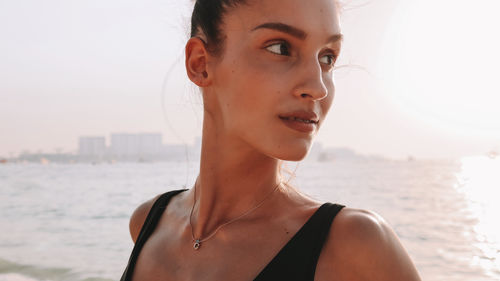 Portrait of beautiful woman at beach against sky