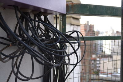 Close-up of metal chain against fence in city