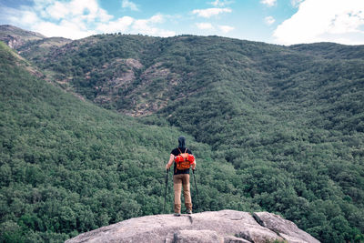 Rear view of man standing on mountain against sky