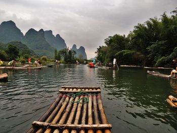 Wooden rafts in river against cloudy sky