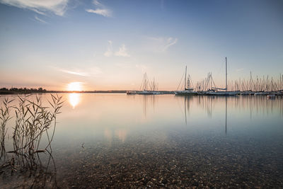 Sailboats in sea against sky during sunset