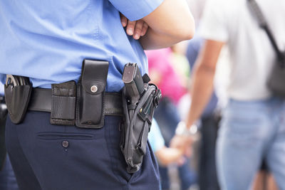 Midsection of police with handgun standing outdoors