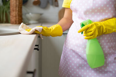 Midsection of woman holding yellow while standing at home