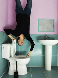 Woman upside down on toilet bowl in bathroom