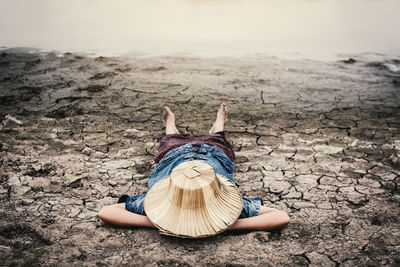 Girl lying down by pond on drought field