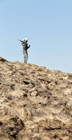 Man standing on rock against clear sky