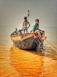 People in boat on sea against sky