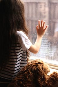 Girl touching glass window while sitting at home