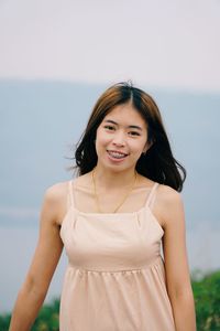 Portrait of a smiling young woman standing against sea