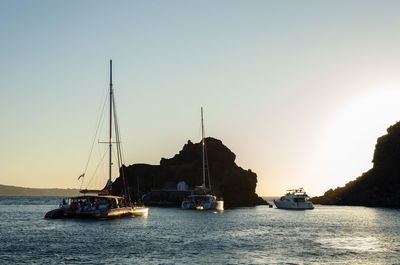 Sailboats sailing in sea against clear sky