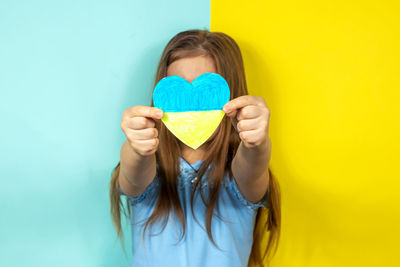 Portrait of young woman wearing hat against yellow background