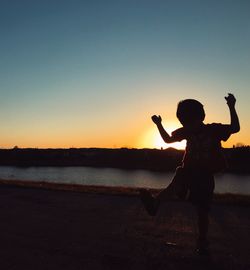 Silhouette of woman jumping at sunset