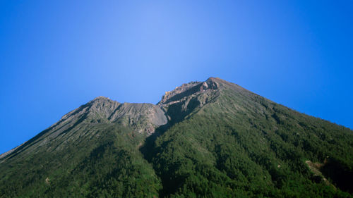 Low angle view of mountains against clear blue sky