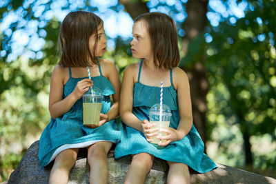 Two little girls drinking lemonade in park