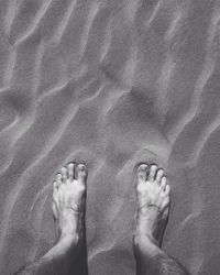 Low section of person relaxing on sand at beach