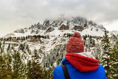 Rear view of person looking at snowcapped mountain against cloudy sky