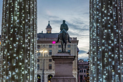 Statue of illuminated building against sky in city