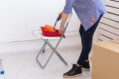 Low section of woman standing holding paint roller standing at home
