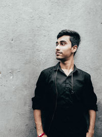 Portrait of young man looking away against wall