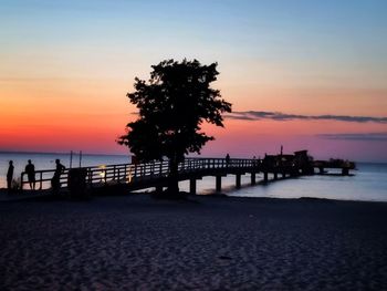 Silhouette pier on beach against sky during sunset