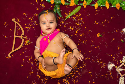 Cute indian boy dresses as lord rama with bow and flowers from top angle