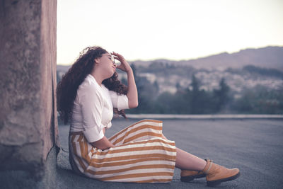 Young woman with curly sitting outdoors 