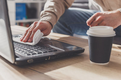 Midsection of man using laptop on table