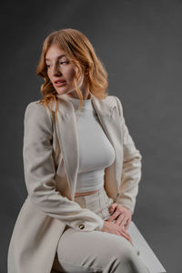 Portrait of young woman standing against gray background