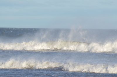 Waves splashing on sea against sky