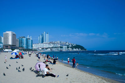 People at beach against blue sky