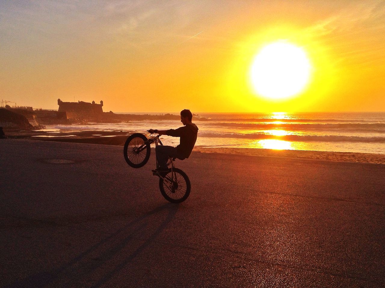 sunset, sea, horizon over water, beach, sun, water, bicycle, transportation, shore, silhouette, orange color, mode of transport, sky, leisure activity, land vehicle, scenics, sunlight, lifestyles