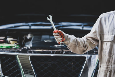 Midsection of mechanic holding wrench in garage