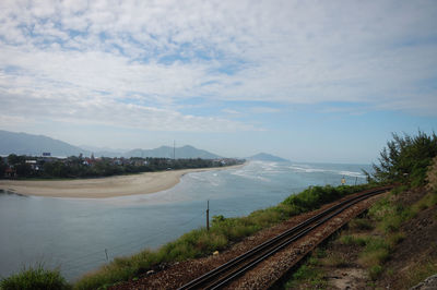 Railroad tracks by sea against sky
