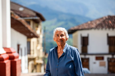 Portrait of young woman standing against building