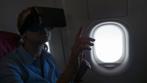Woman gesturing while using virtual reality in airplane
