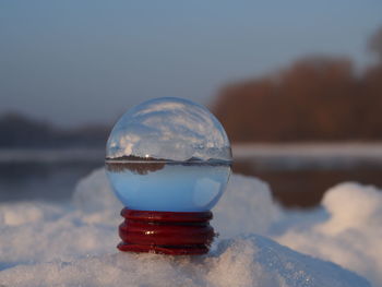 Close-up of crystal ball against sky during winter