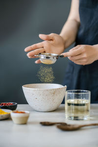 Midsection of woman preparing food in bowl on table