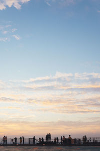 Silhouette of people in city against sky during sunset