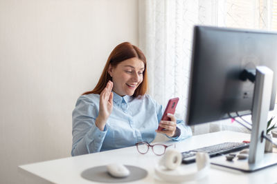 Young woman using phone while sitting on table