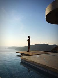 Side view of silhouette mature man standing at poolside against sky during sunset